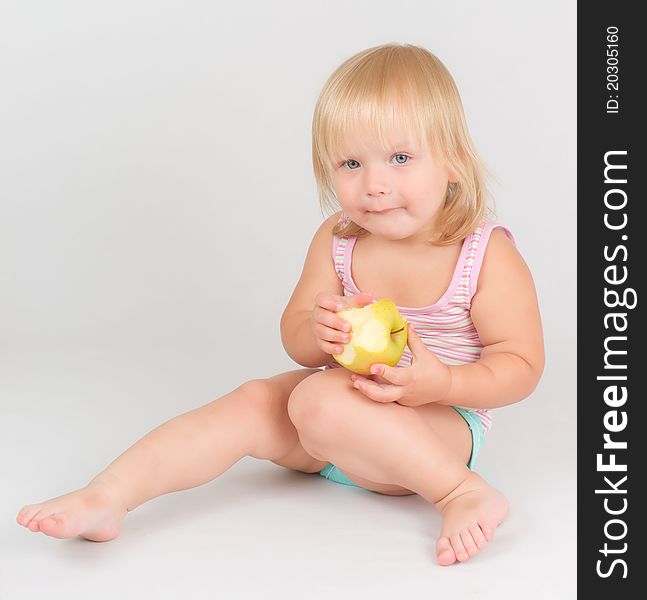 Adorable toddler girl eat green fresh apple sitting on white