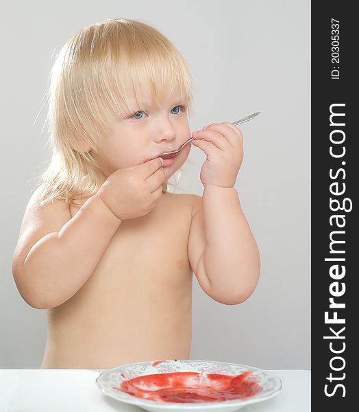 Adorable toddler girl eat strawberry jam with spoon from plate. Adorable toddler girl eat strawberry jam with spoon from plate