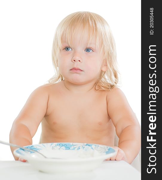 Adorable toddler girl eat porridge with spoon from plate