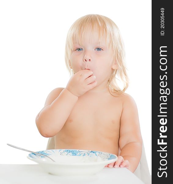 Adorable toddler girl eat porridge with spoon from plate