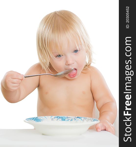 Adorable toddler girl eat porridge with spoon from plate