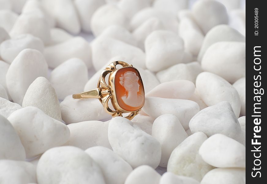 A gold ring with cameo on white pebbles