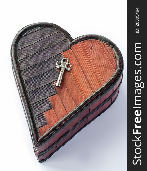 A small key on a wooden heartshaped box. A small key on a wooden heartshaped box