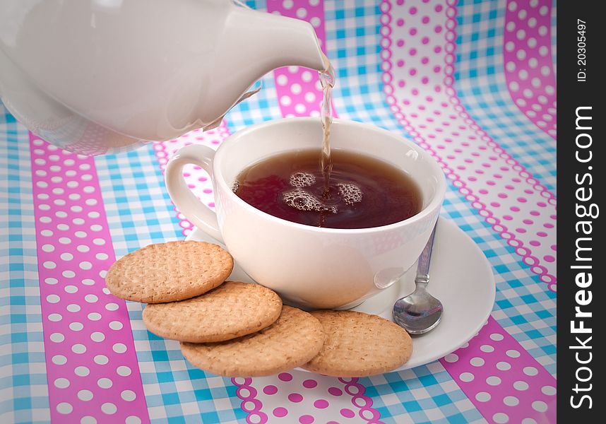Pouring a cup of tea, with cookies on the side