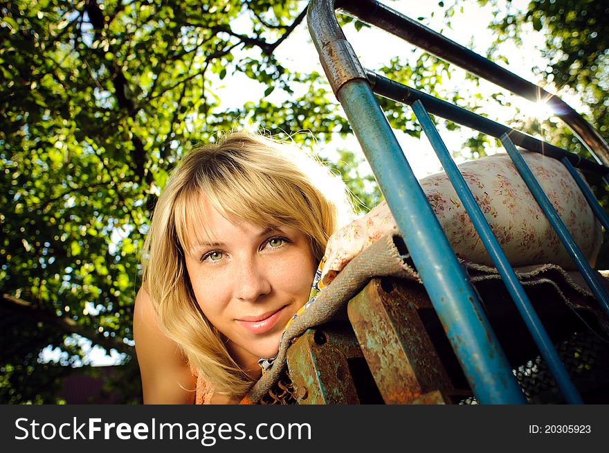 Young woman lying on a rusty bed outdoors. Young woman lying on a rusty bed outdoors