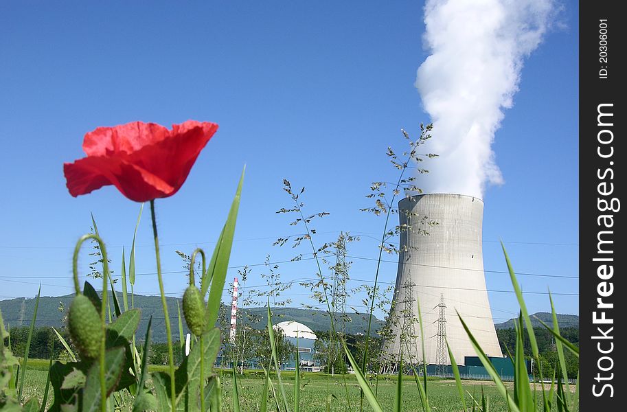 Nuclear power plant with red poppy flower in the foreground. Nuclear power plant with red poppy flower in the foreground