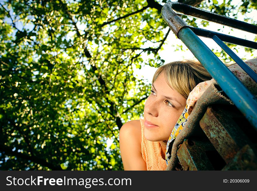 Young woman lying on a rusty bed outdoors. Young woman lying on a rusty bed outdoors