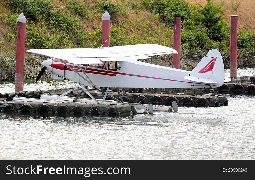 A white seaplane or float plane parked at a dock. A white seaplane or float plane parked at a dock.