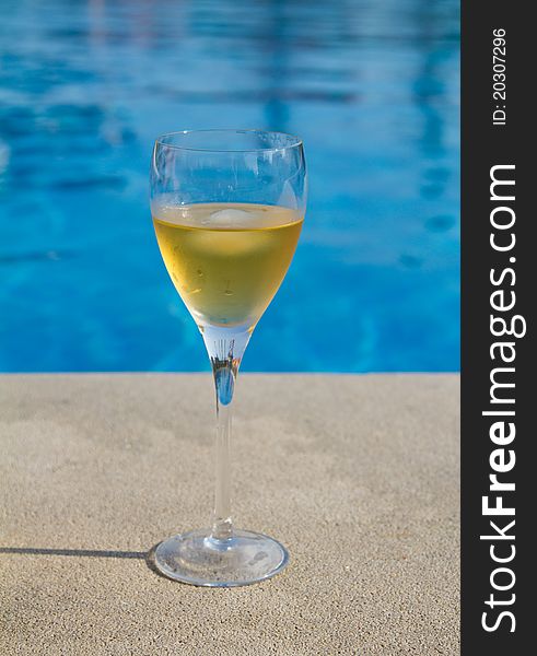 Glass of white wine next to the pool. Glass of white wine next to the pool
