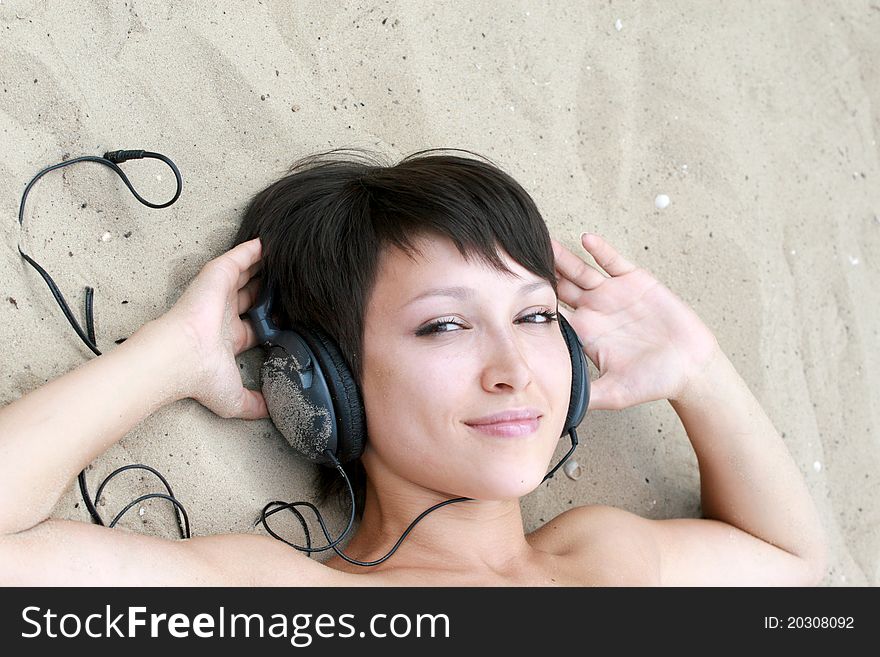 Young girl with ear-phones on the sand