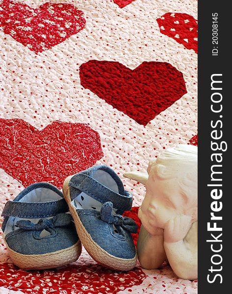 Denim shoes with ceramic angel on a quilt with red and white hearts  . Denim shoes with ceramic angel on a quilt with red and white hearts