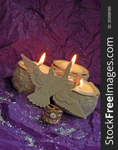 Purple glittery background with wedding rings candles and doves. Purple glittery background with wedding rings candles and doves