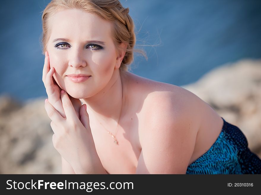 Pretty woman sitting on the rocky mountain near the sea