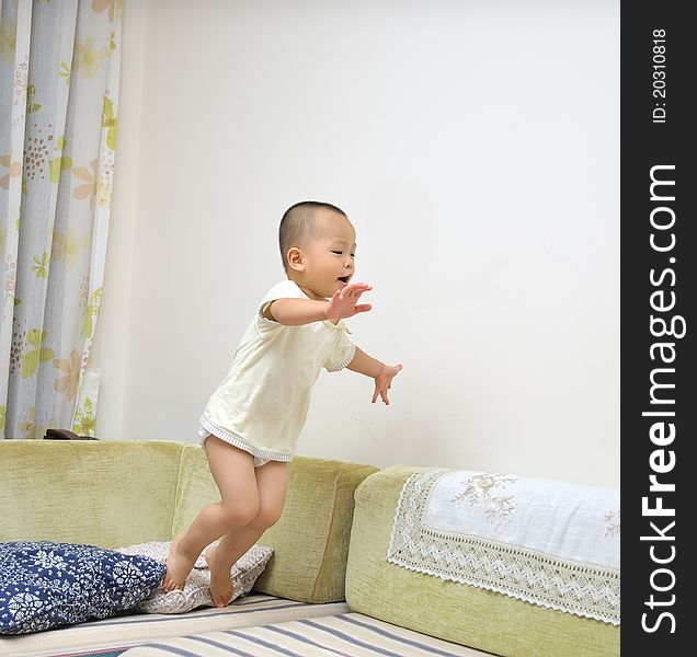 A chinese boy is jumping from sofa. A chinese boy is jumping from sofa.