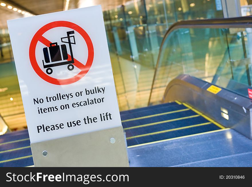 A warning signboard before the escalator at the airport, advising tourists with trolleys or bulky items to use the lift instead. A warning signboard before the escalator at the airport, advising tourists with trolleys or bulky items to use the lift instead.