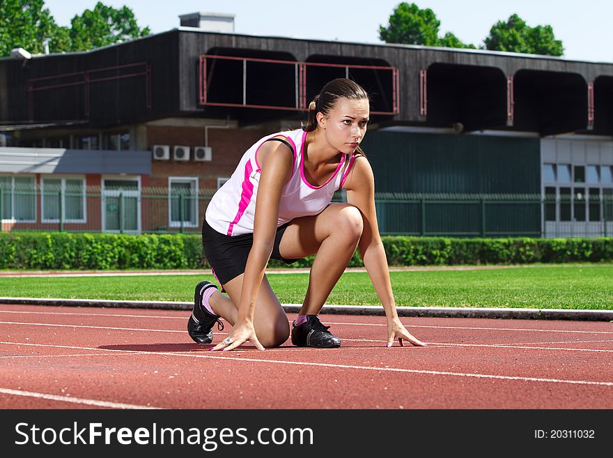 Young woman in sprinting position on the track