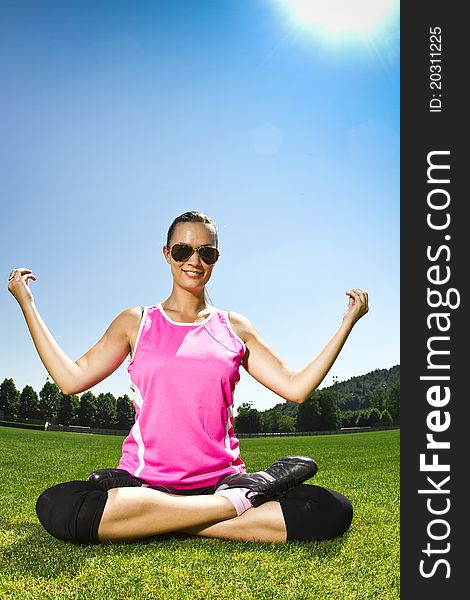 Young woman on the freshly cut grass stretching after exercise