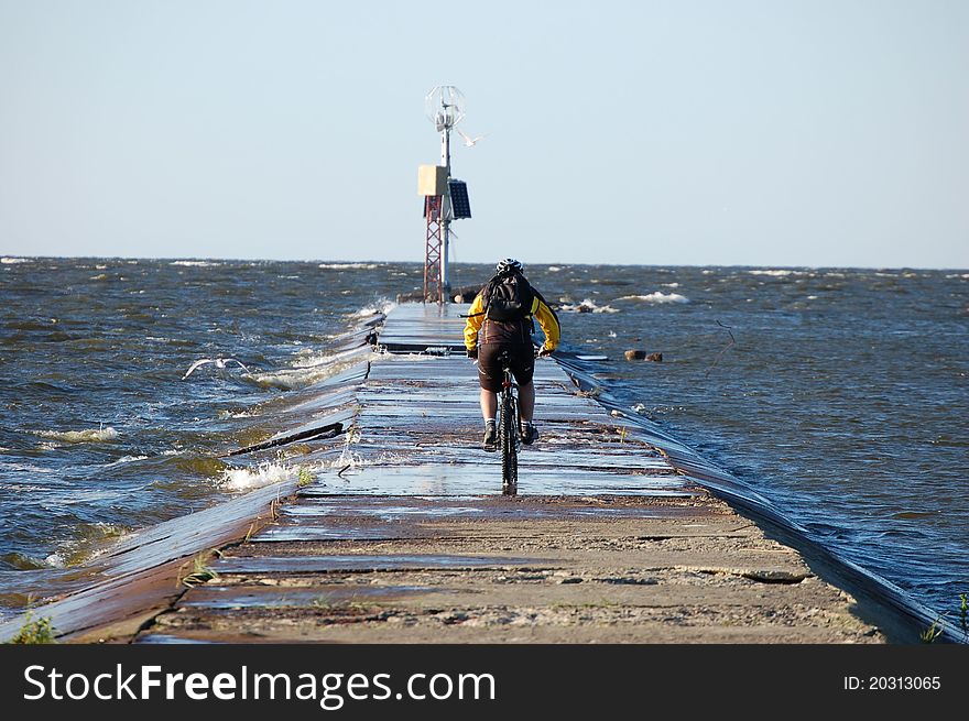 Cyclist on a promontory near the river flowing into the sea. Cyclist on a promontory near the river flowing into the sea