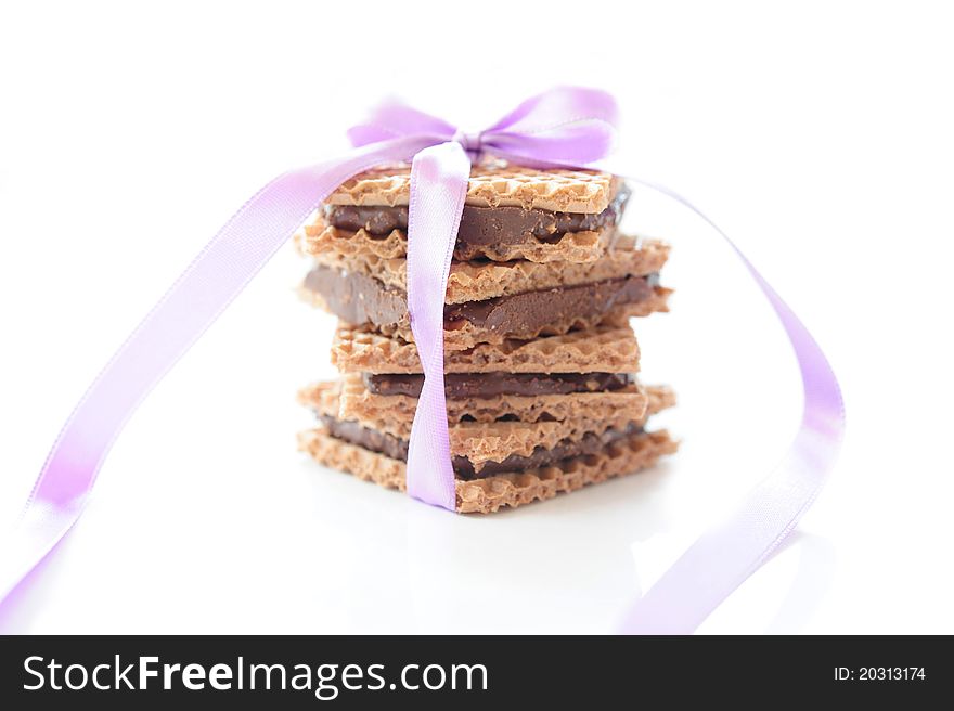 Square waffle with chocolate and nut filling, tied with purple ribbon on a white background. Square waffle with chocolate and nut filling, tied with purple ribbon on a white background