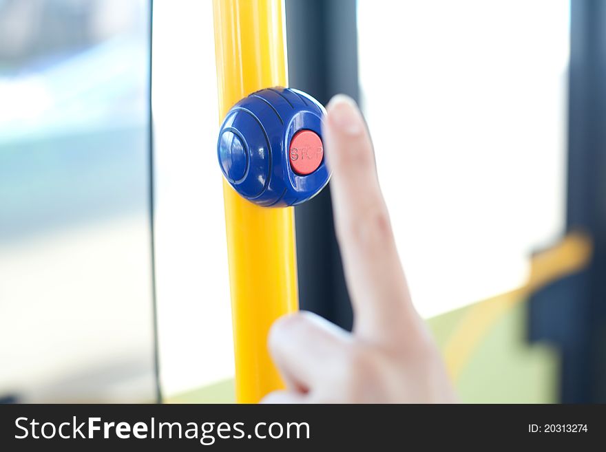 Finger and stop button at a handhold inside a bus