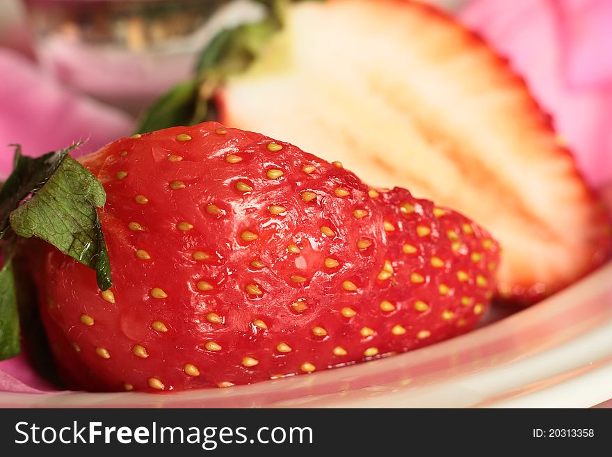 Image of a large tasty strawberry ready for eating on a pink and white plat. Image of a large tasty strawberry ready for eating on a pink and white plat