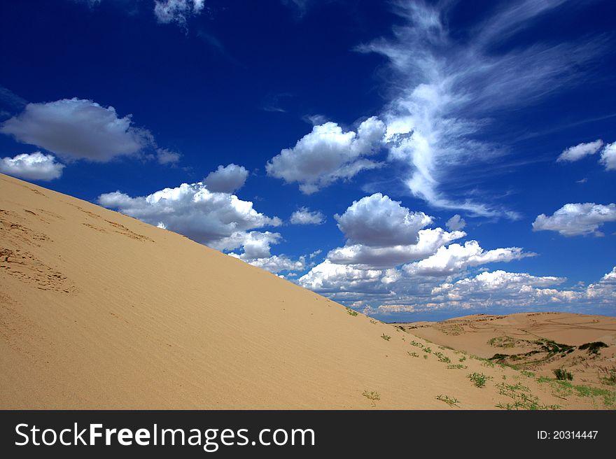 The beautiful desert scenery with blue sky, white cloud and yellow sand