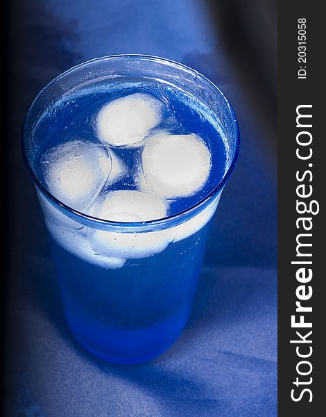 Blue glas of water with ice-cubes on a blue background. Blue glas of water with ice-cubes on a blue background