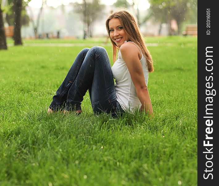 Cheerful woman in the park under the rain. Cheerful woman in the park under the rain