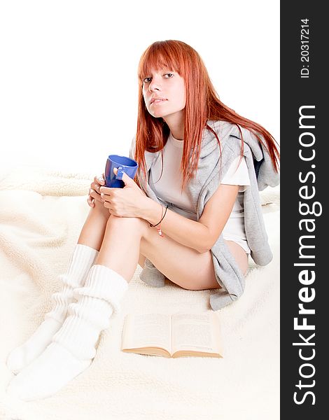 Young beautiful female sitting, reading a book and holding a cup