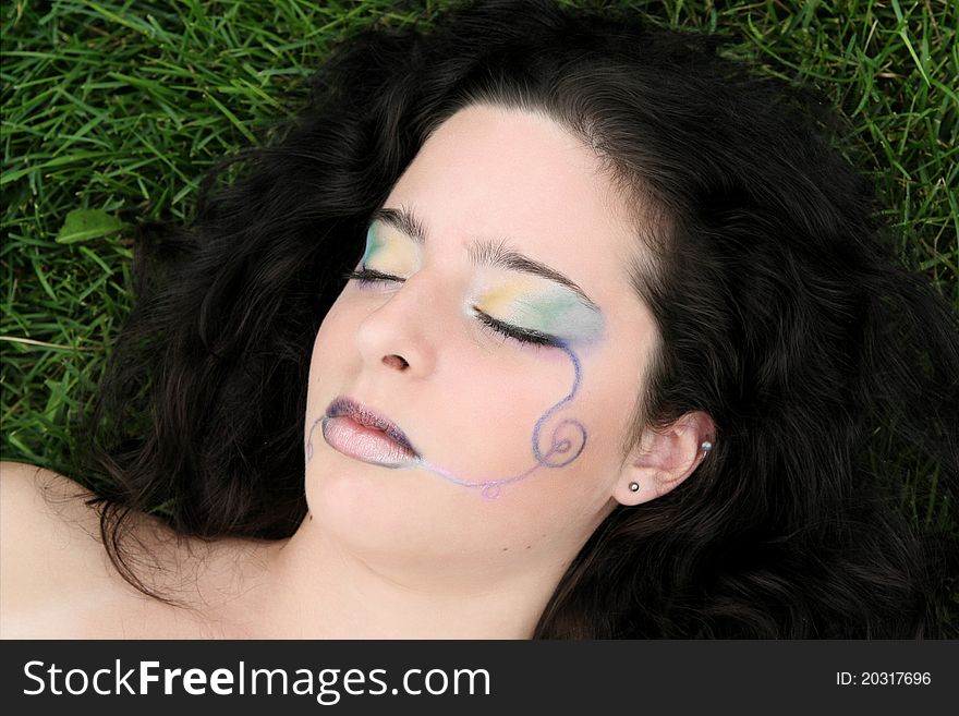 A young woman sleeping in the grass, a rainbow of colors on her face. A young woman sleeping in the grass, a rainbow of colors on her face.