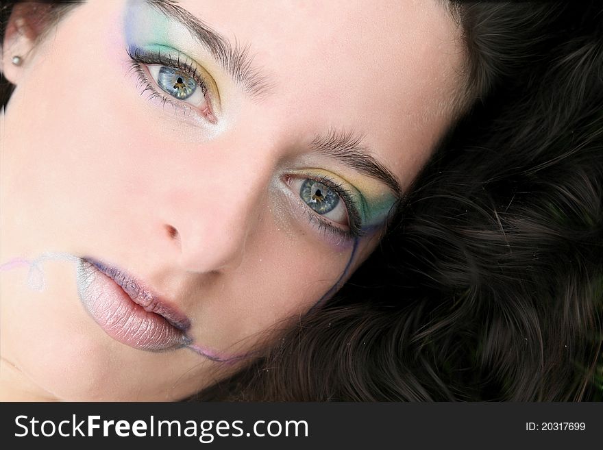 Close up of a young woman, hair surrounding her face, colorful makeup. Close up of a young woman, hair surrounding her face, colorful makeup.
