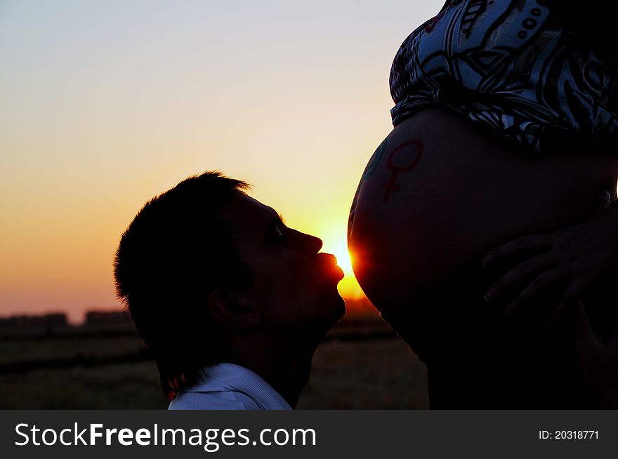 The husband kisses the pregnant wife on a stomach. The husband kisses the pregnant wife on a stomach
