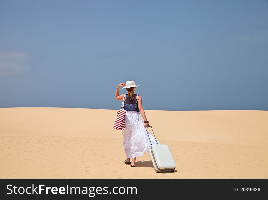 Woman walking on a sand with luggage. Woman walking on a sand with luggage