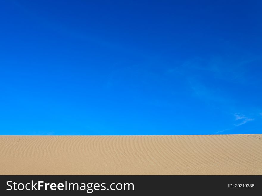 Bird footprint in the sand at a clear blue sky