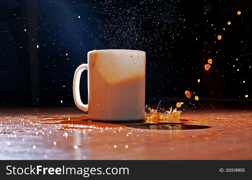 Splash made by ice in cup filled with coffee on the table. Splash made by ice in cup filled with coffee on the table