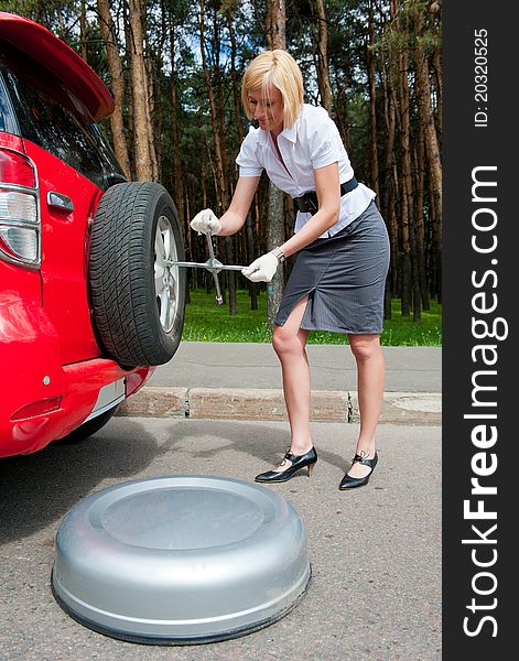 Blonde changing tire alone on a road. Blonde changing tire alone on a road