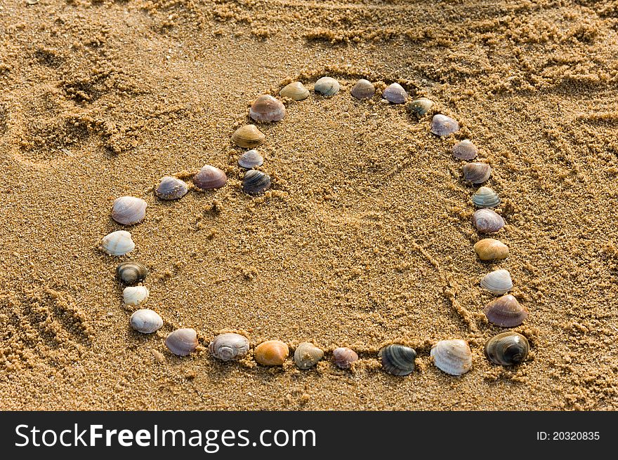 Shell on the sand putten to the love symbol heart. Shell on the sand putten to the love symbol heart