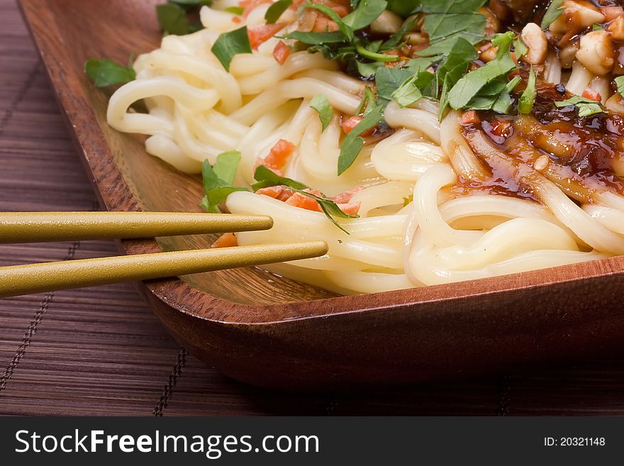 Freshly prepared Asian noodles next to golden chopsticks.