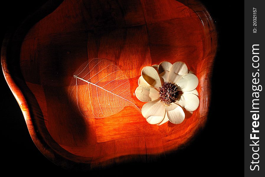 Wooden leaf and flower in wooden dish filled with water