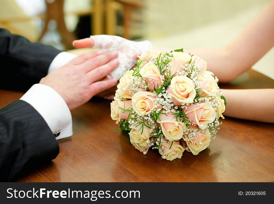 Newly-married couple sits at a table in cafe and on a table the bouquet of the bride lies. Newly-married couple sits at a table in cafe and on a table the bouquet of the bride lies