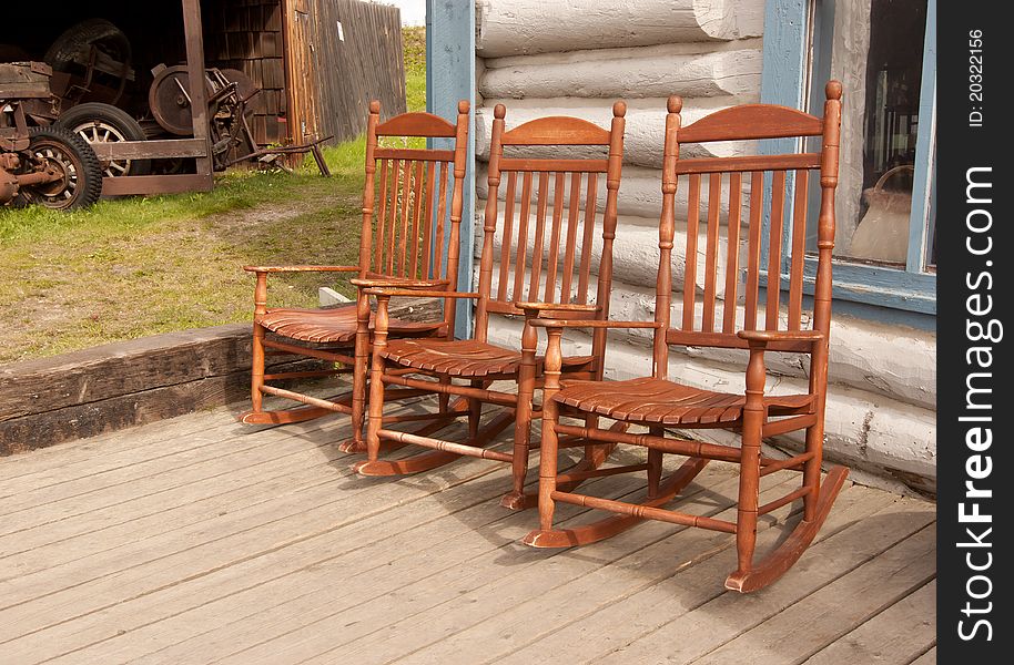 Three rocking chairs on a porch ready for someone to relax in