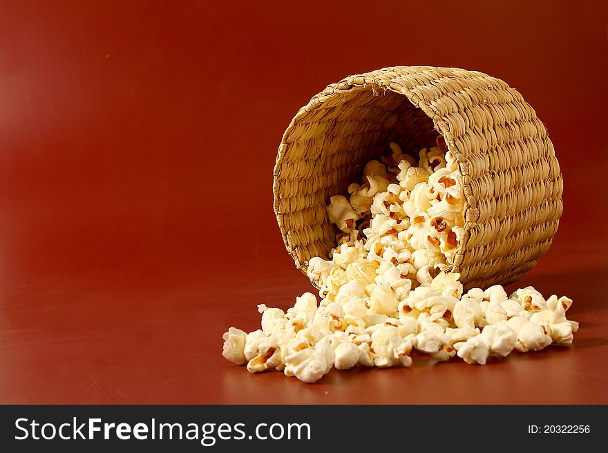 Spread popcorn on red background with basket