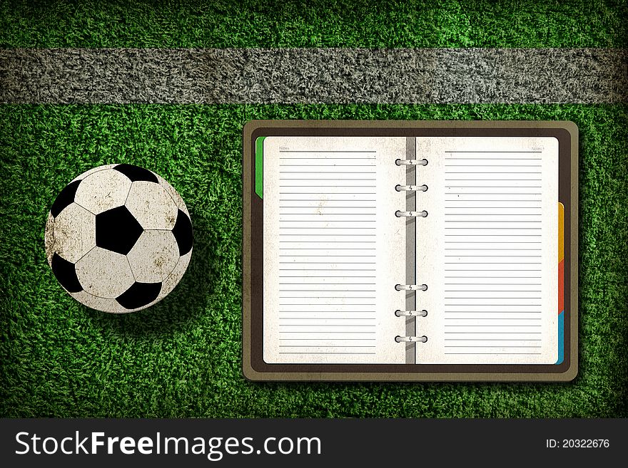 Football and blank notebook on Green Grass background