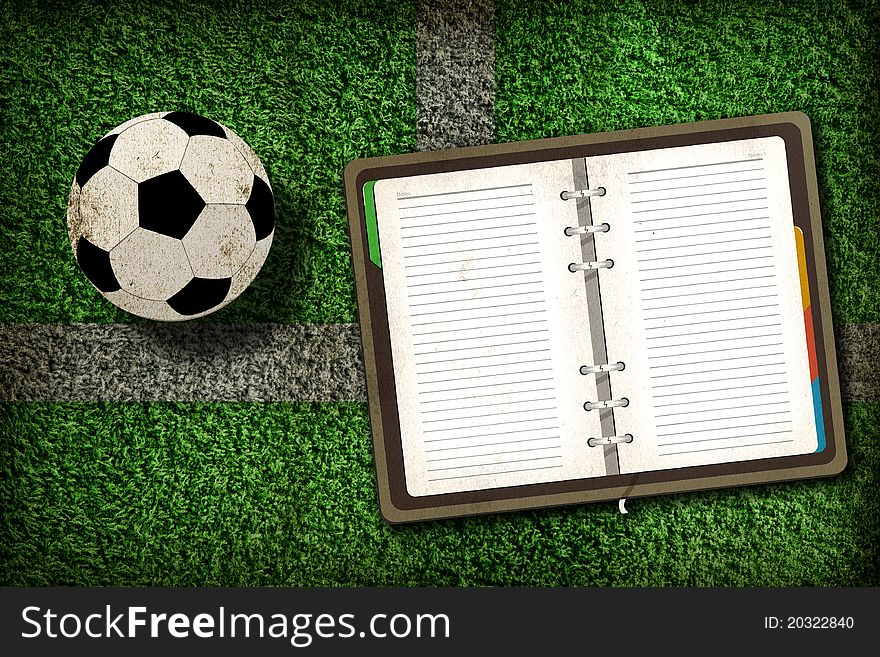 Football and blank notebook on Green Grass background