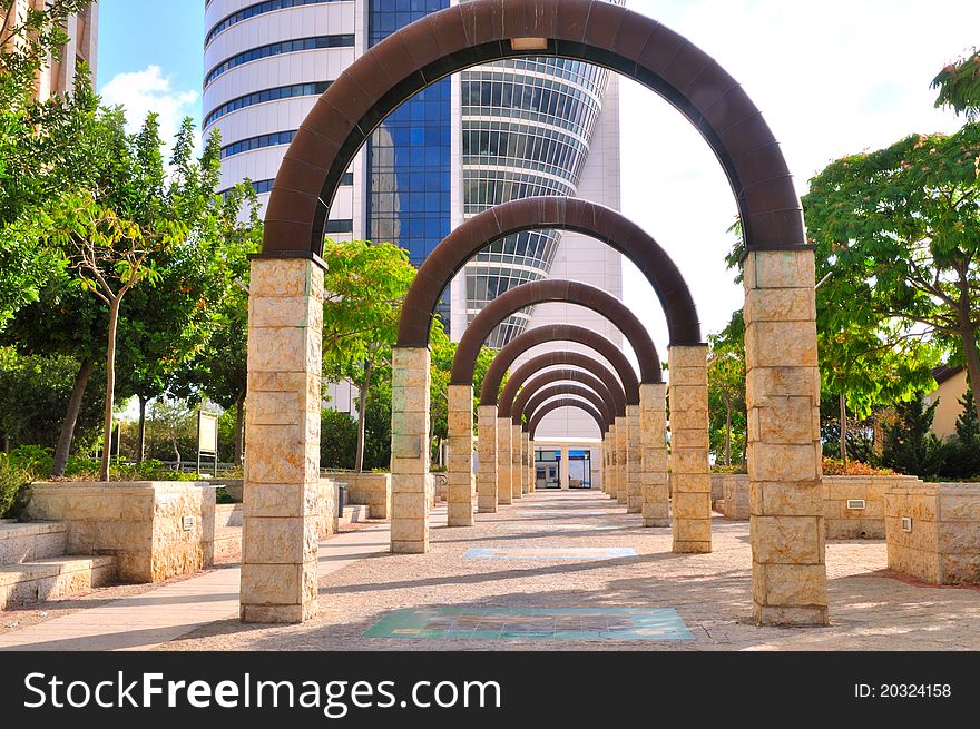 Alley of metal arches on stone pillars leading to an office building. Alley of metal arches on stone pillars leading to an office building