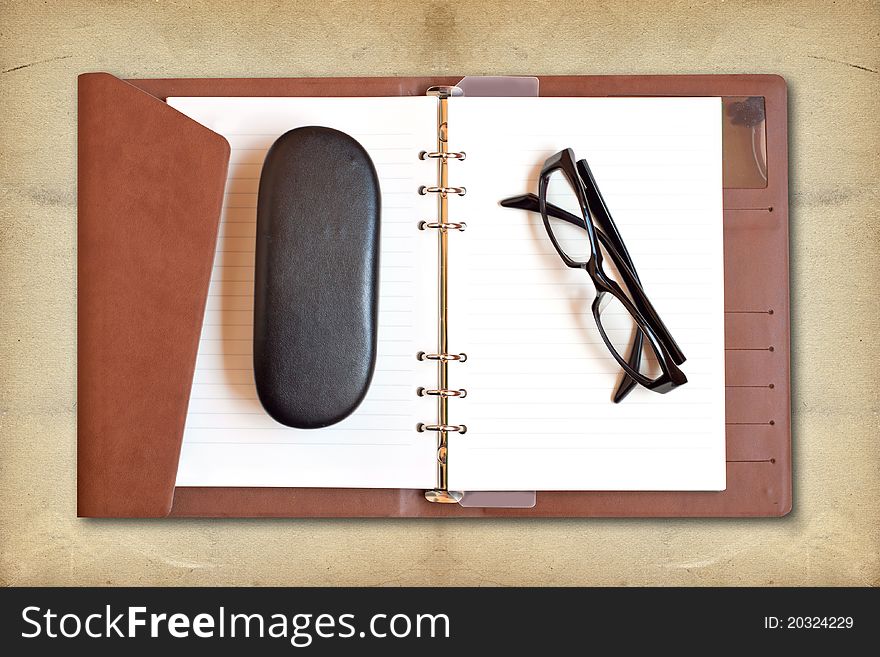 Reading glasses on white notebook