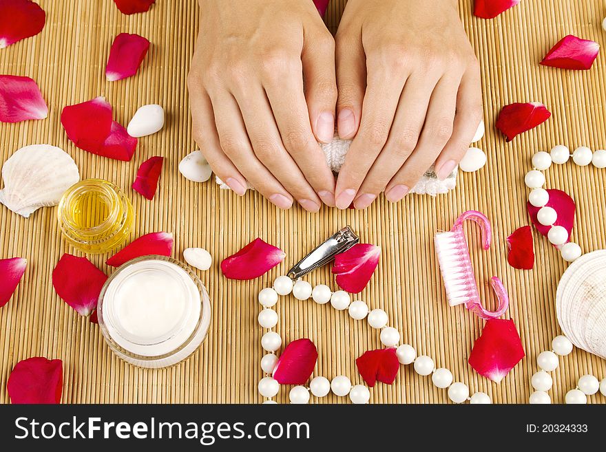 Close-up of girl lying on hand towel next to the cream, rose petals and manicure equipment. Close-up of girl lying on hand towel next to the cream, rose petals and manicure equipment