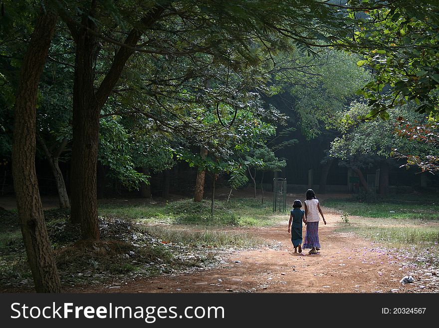 Two girls taking leisurely stroll in green surroundings of a park. Two girls taking leisurely stroll in green surroundings of a park