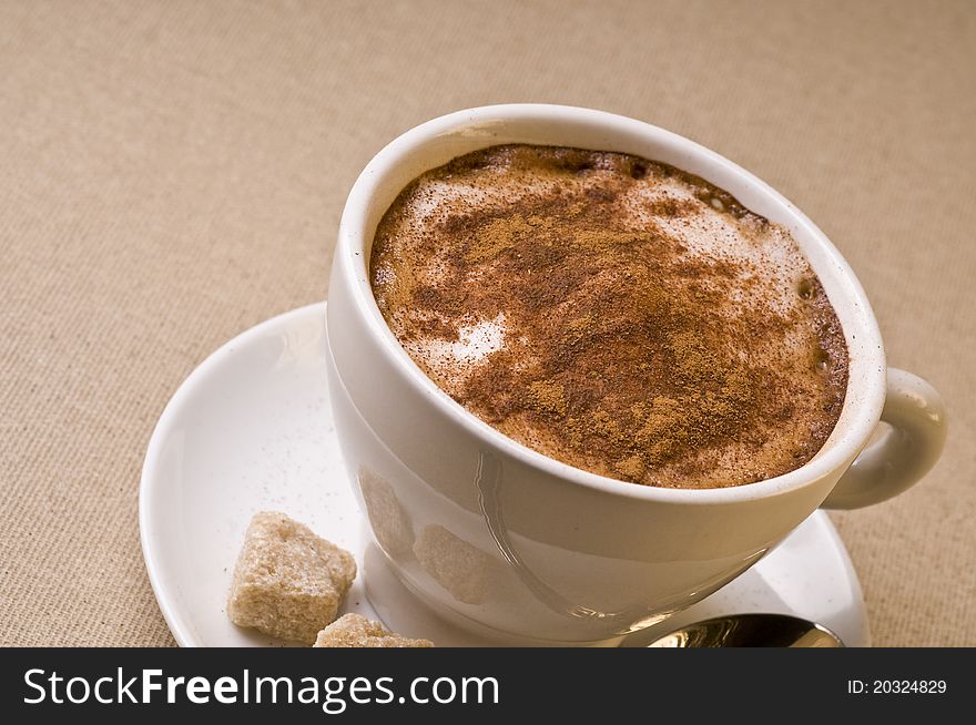 Cappuccino coffee cup with froth over brown background