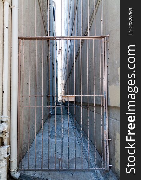 Looking down a long gated alleyway that is deserted.